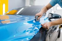 car-wrapping-mechanic-with-squeegee-installs-protective-vinyl-foil-film-vehicle-hood-worker-makes-auto-detailing-automobile-paint-protection-coating-professional-tuning